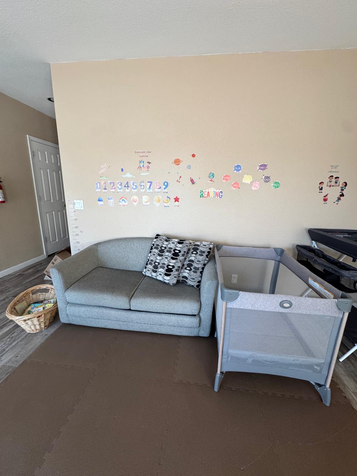Quiet rest corner with a sofa, a basket of books, and playful wall decals