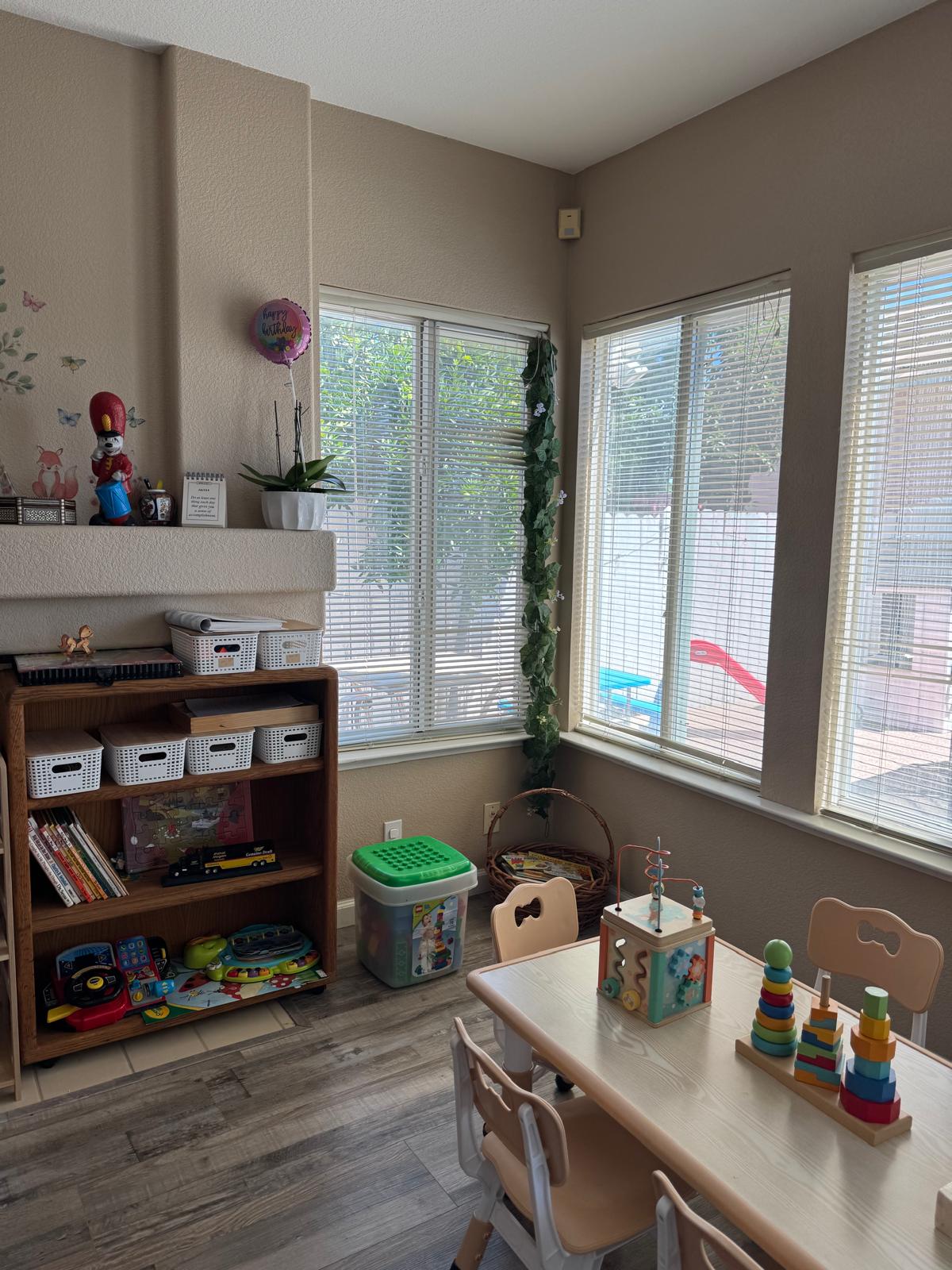 Bookshelf and activity table in a bright corner near the play yard window